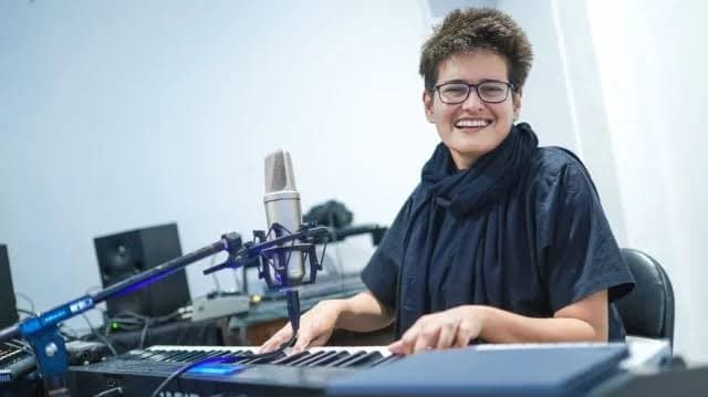 Shayan smiling at a keyboard in a recording studio
