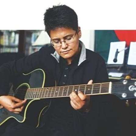 Shayan playing an acoustic guitar in a study